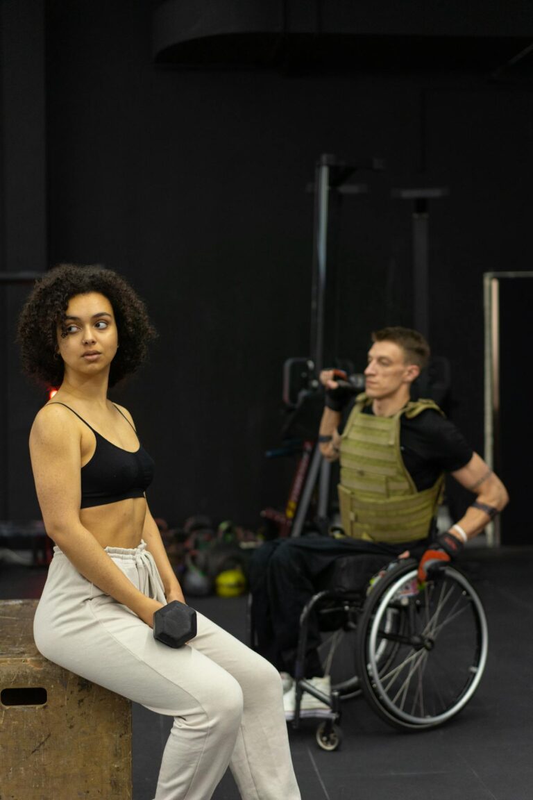 A woman and a man in a wheelchair working out together in a gym.
